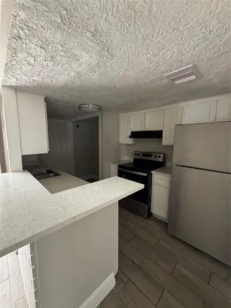 a kitchen with stainless steel appliances kitchen island granite countertop a refrigerator a stove and a sink