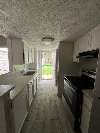 a kitchen with granite countertop a stove sink and cabinets