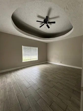 an empty room with wooden floor fan and windows