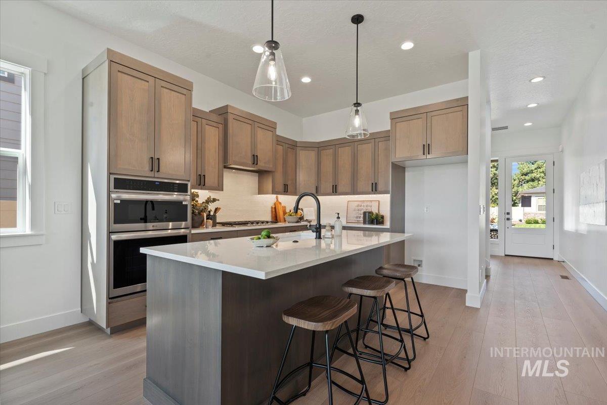 677 North Morning Glory Way Eagle, ID 83616 - Photo 9 of 29 Kitchen with pendant lighting, a breakfast bar, an island with sink, light wood-style floors, and double oven