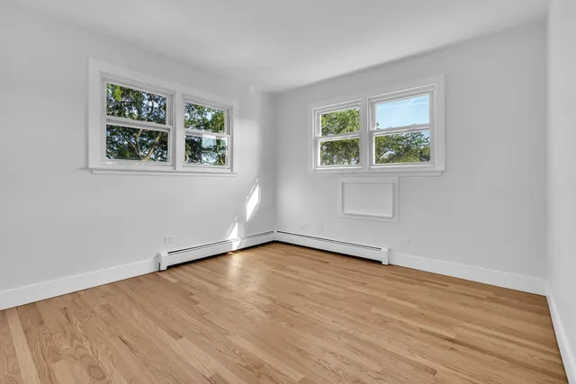 an empty room with wooden floor and window