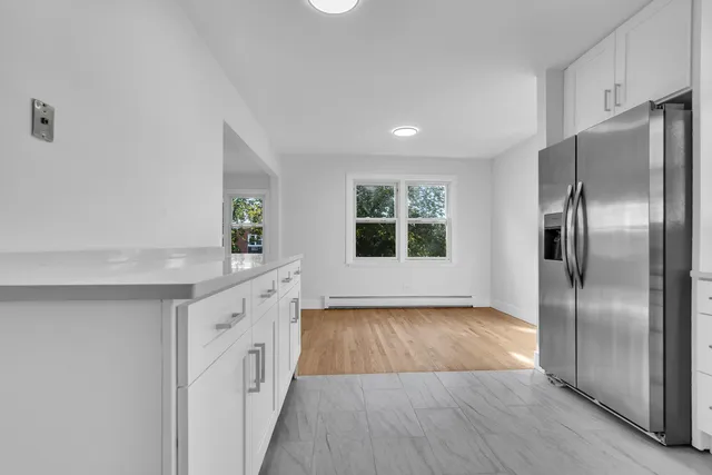 a kitchen with granite countertop a refrigerator a sink a stove and wooden floor