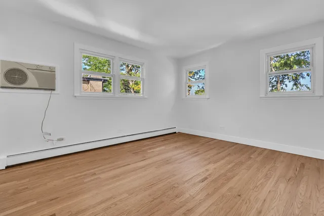 an empty room with wooden floor and window