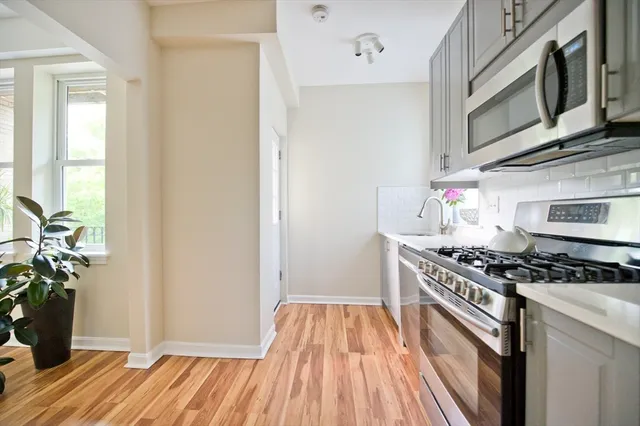 a kitchen with stainless steel appliances granite countertop a stove and a wooden floor