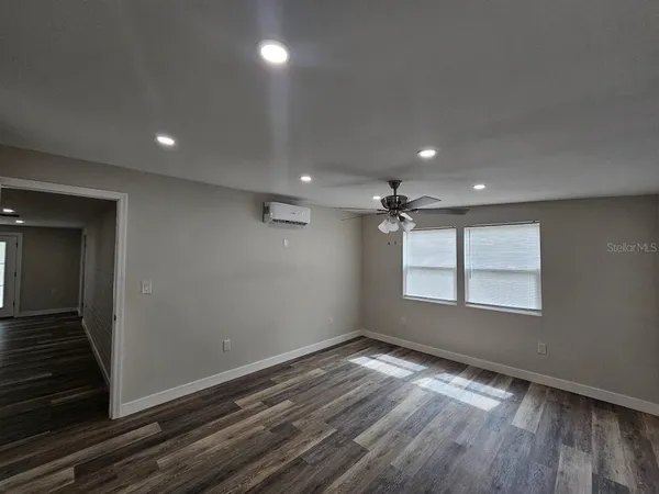 an empty room with wooden floor and windows