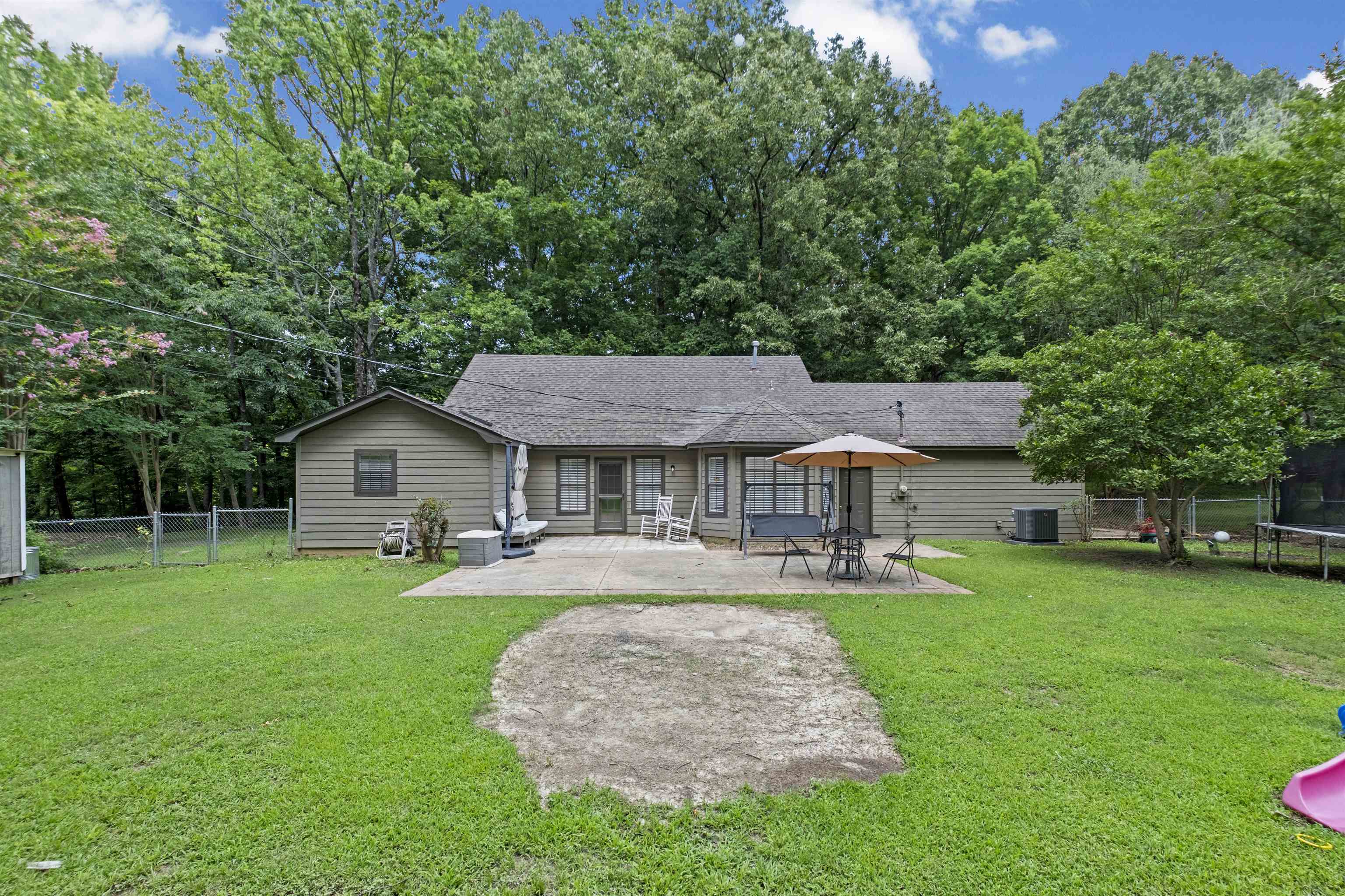 3601 Marshall Road Munford, TN 38058 - Photo 10 of 35 Rear exterior featuring a spacious concrete patio, a private fenced yard, mature trees, and an accessory building
