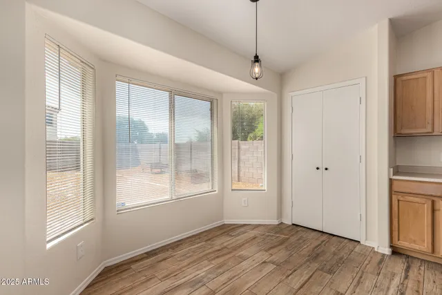 a view of an empty room with a window and wooden floor
