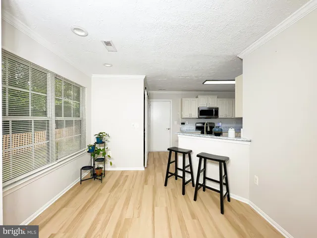 a kitchen with stainless steel appliances a dining table chairs and a refrigerator