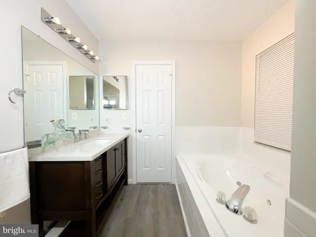 a bathroom with a tub a sink and mirror