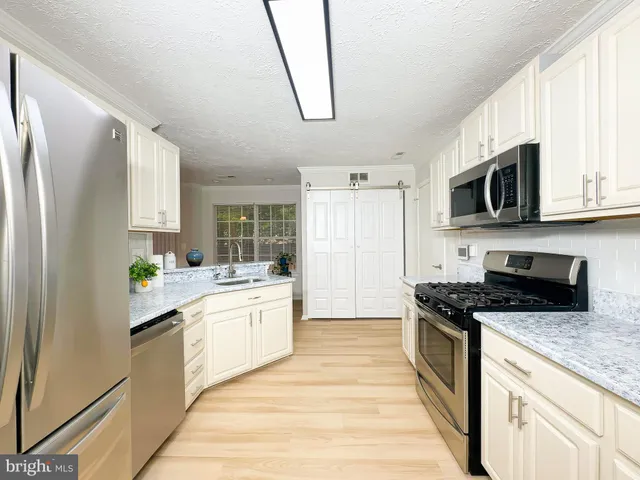 a kitchen with stainless steel appliances a stove a sink dishwasher a refrigerator and a microwave