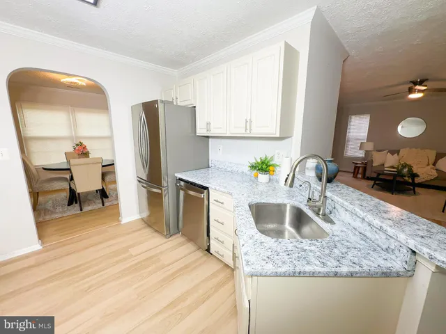 a kitchen with stainless steel appliances granite countertop a sink dishwasher and a refrigerator with wooden cabinets