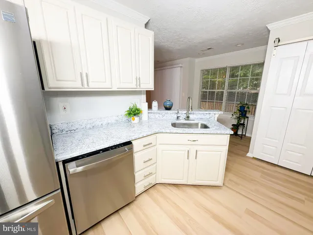 a kitchen with granite countertop white cabinets and white appliances
