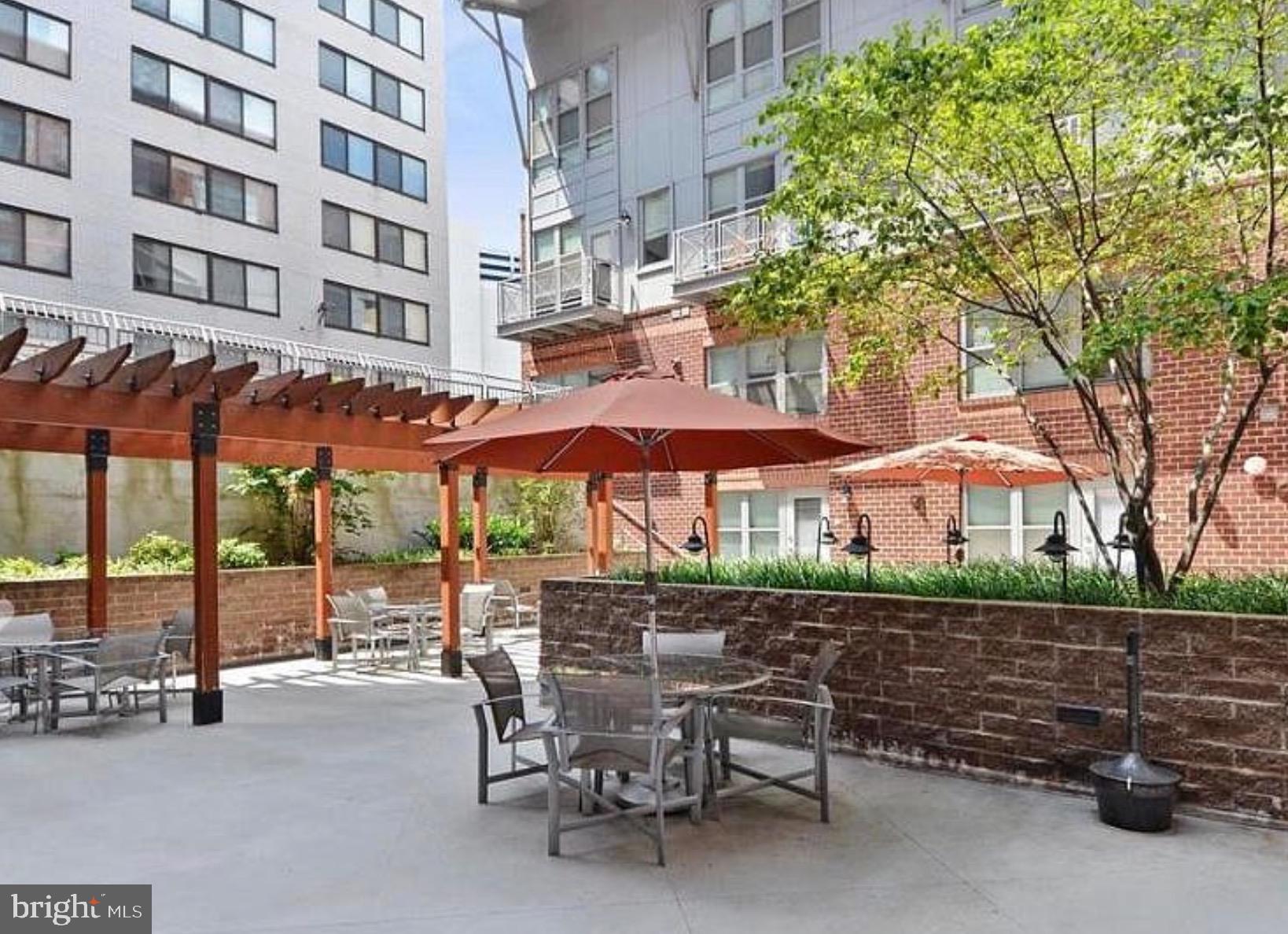 1300 N Street Northwest, Unit 21 Washington, DC 20005 - Photo 2 of 21 a view of a chairs and table under an umbrella in front of a building