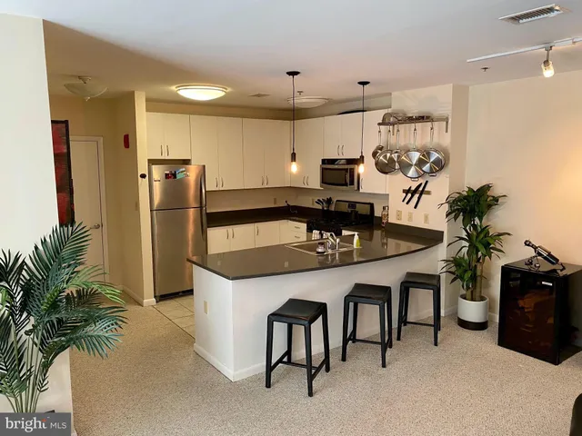 a kitchen with stainless steel appliances granite countertop a table chairs stove and refrigerator