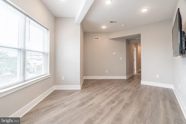 a view of an empty room with wooden floor and window