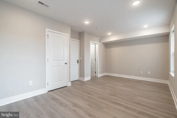 an empty room with wooden floor and windows