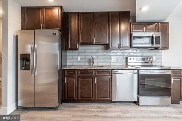 a kitchen with stainless steel appliances granite countertop a refrigerator and a sink