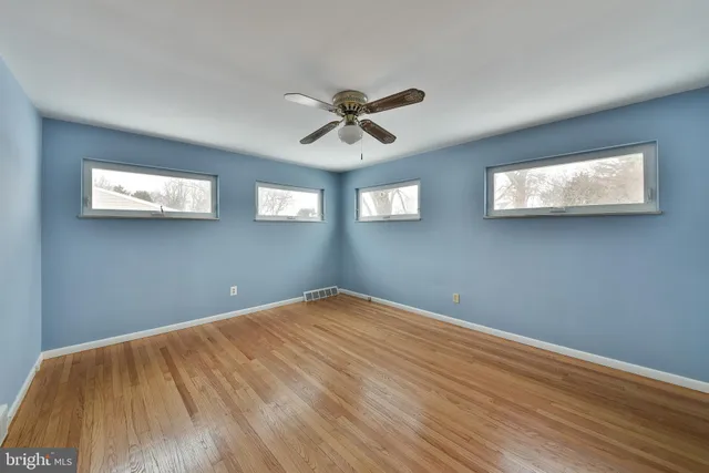 a view of a big room with wooden floor and windows
