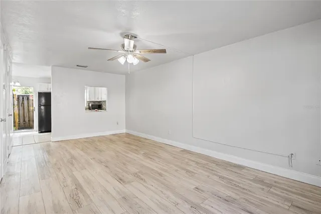 wooden floor in an empty room with a chandelier fan