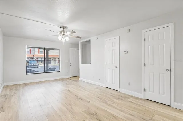 a view of an empty room with a window and wooden floor