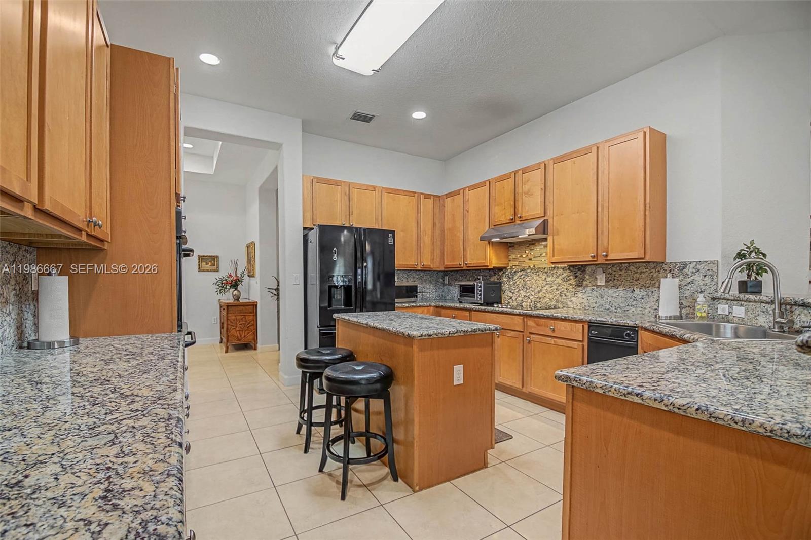 19528 Southwest 79th Place Cutler Bay, FL 33157 - Photo 11 of 41 a kitchen with stainless steel appliances granite countertop a refrigerator a stove a sink a dining table and chairs