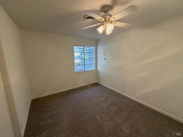 an empty room with windows and fan