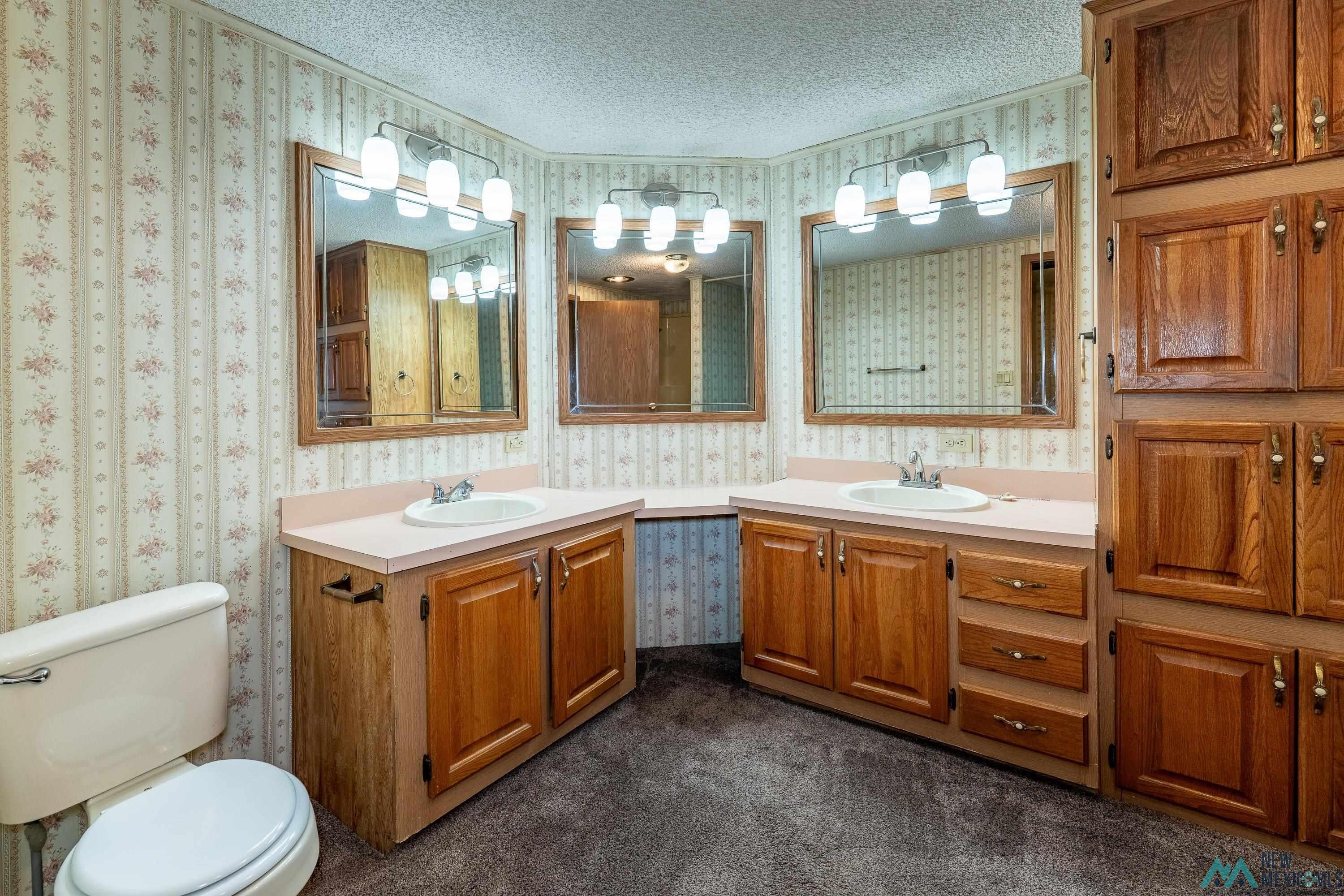 35234 Highway 87 Raton, NM 87740 - Photo 54 of 90 Bathroom with two vanities, wallpapered walls, and a textured ceiling