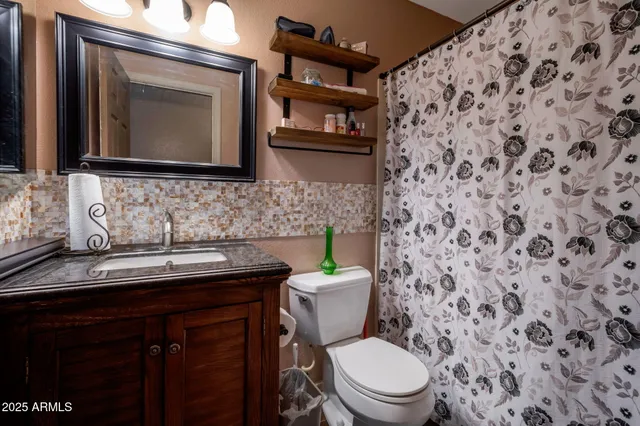 a bathroom with a granite countertop toilet sink and mirror