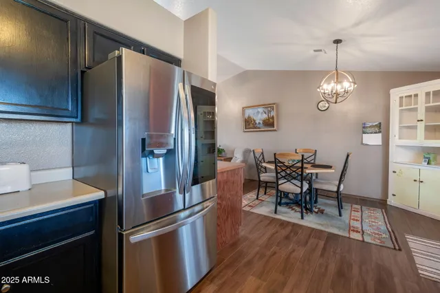 a kitchen with stainless steel appliances granite countertop a refrigerator a stove a dining table and chairs with wooden floor