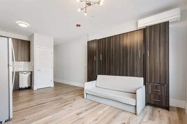 a living room with furniture and a refrigerator