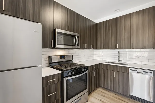 a kitchen with granite countertop wooden cabinets stainless steel appliances and a sink