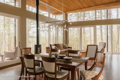 a dining room with furniture large windows and wooden floor