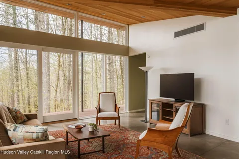 a living room with furniture a flat screen tv and a floor to ceiling window