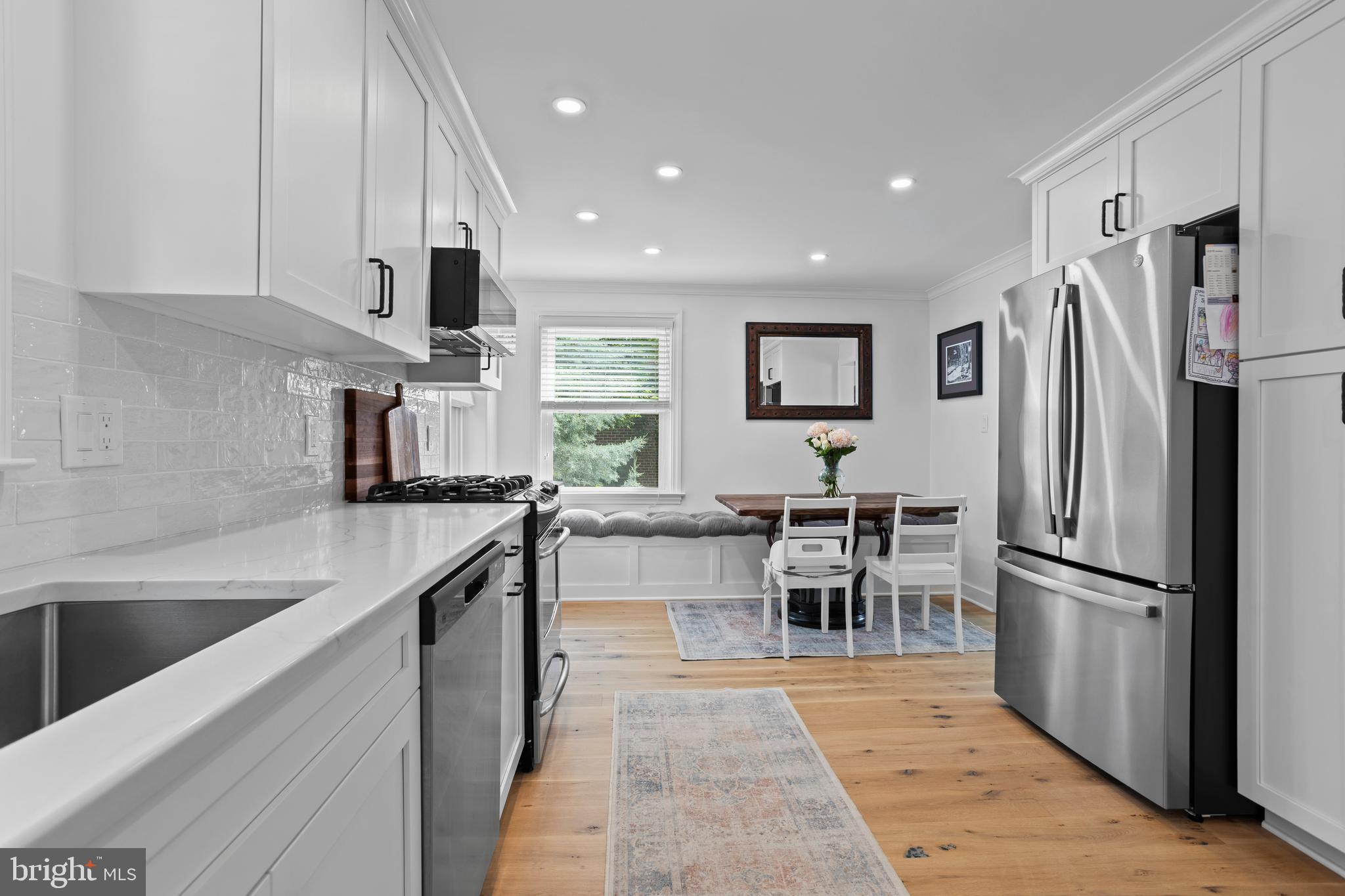 46 Plymouth Road Springfield, PA 19064 - Photo 11 of 30 a kitchen with stainless steel appliances granite countertop a refrigerator oven a sink a dining table and chairs with wooden floor