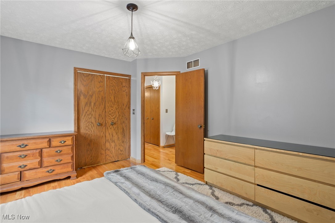 4694 Ranchwood Road Akron, OH 44333 - Photo 36 of 44 Bedroom with wood finished floors, a closet, and a textured ceiling