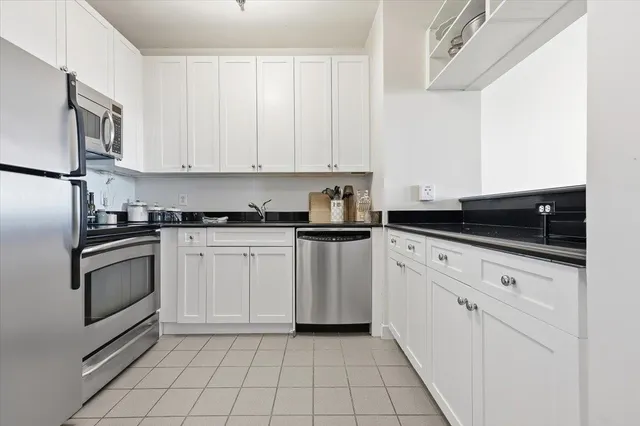 a kitchen with white cabinets and appliances