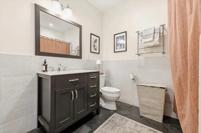 a bathroom with a toilet sink vanity and mirror
