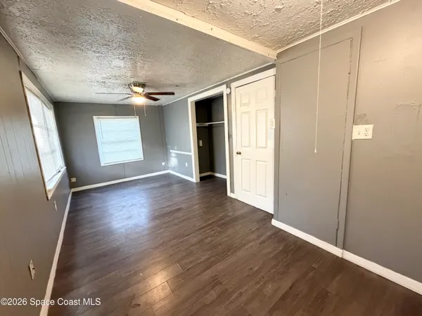 an empty room with wooden floor and windows