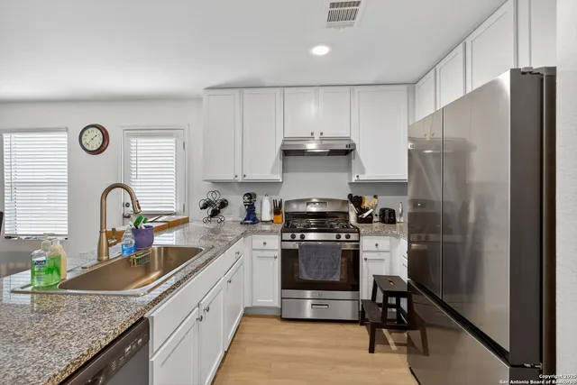 a kitchen with granite countertop a sink dishwasher stove and cabinets with wooden floor