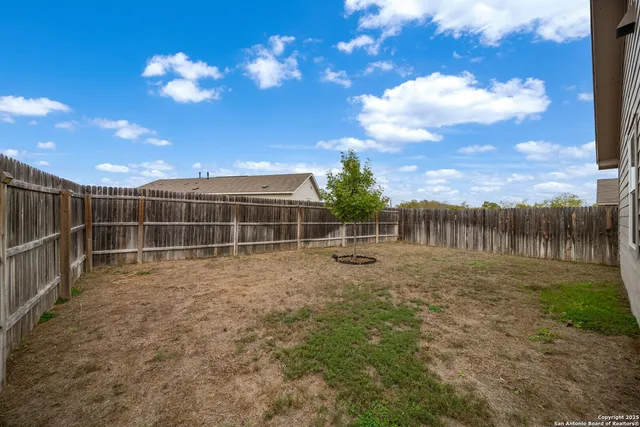 a view of backyard of house with wooden fence