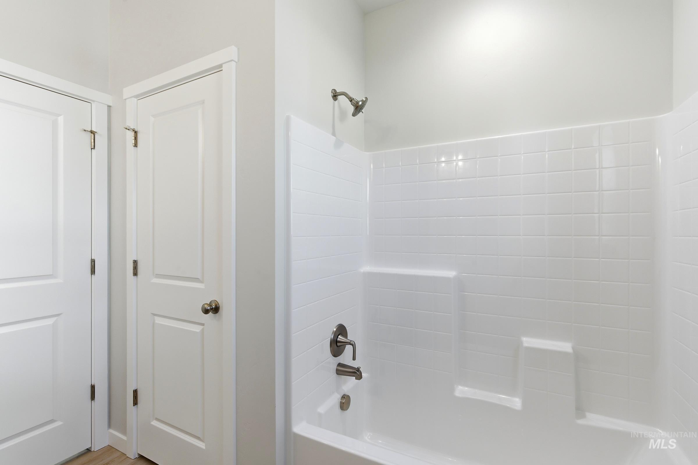 13663 Redway Court Caldwell, ID 83607 - Photo 22 of 32 Bathroom featuring a white subway tile-patterned shower surround with integrated shelving, brushed nickel fixtures, and light wood-finish flooring