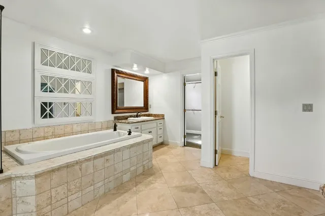 a spacious bathroom with a bathtub sink and mirror