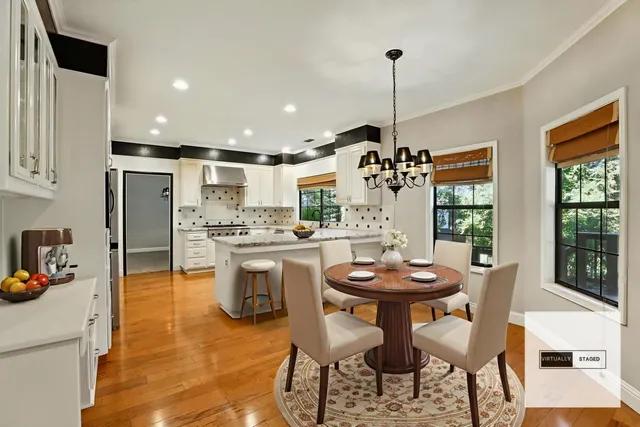 a kitchen with stainless steel appliances kitchen island granite countertop a dining table chairs and white cabinets