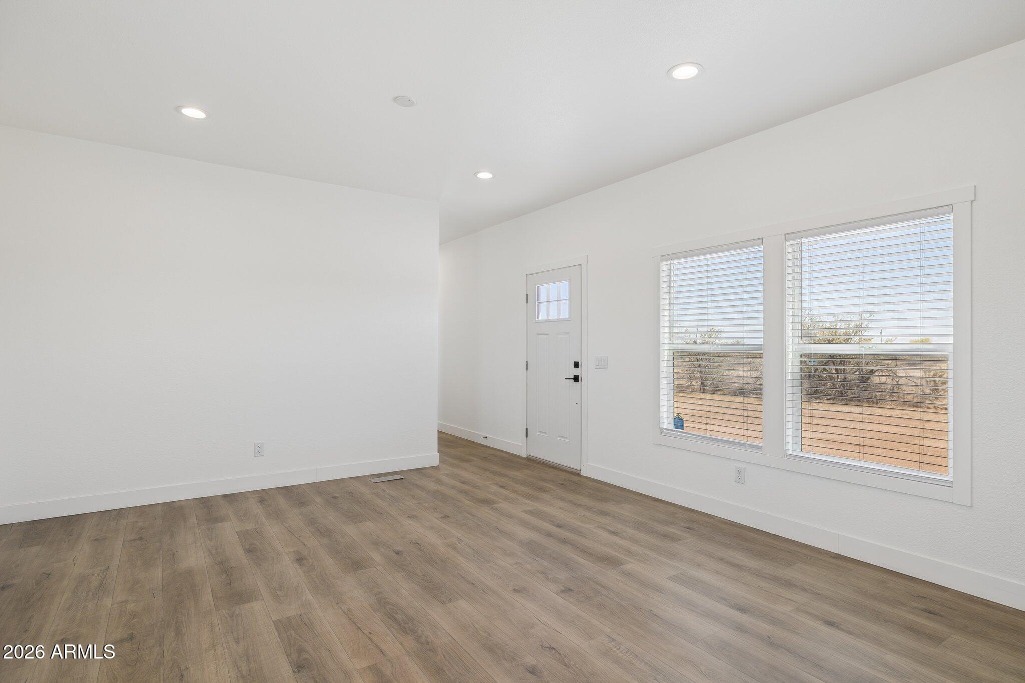 50044 West Century Road Maricopa, AZ 85139 - Photo 11 of 38 an empty room with wooden floor and windows