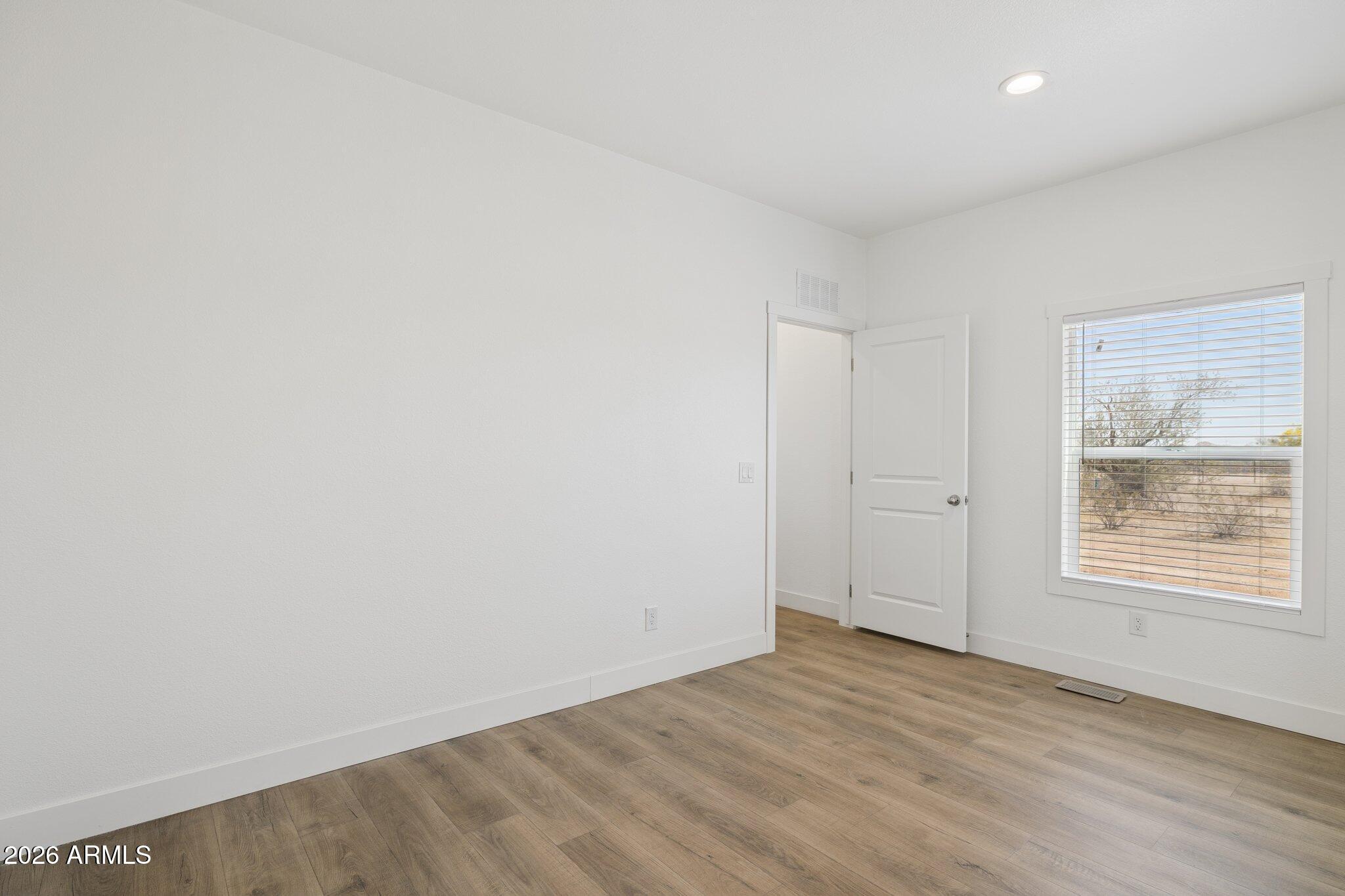 50044 West Century Road Maricopa, AZ 85139 - Photo 19 of 38 an empty room with wooden floor and windows