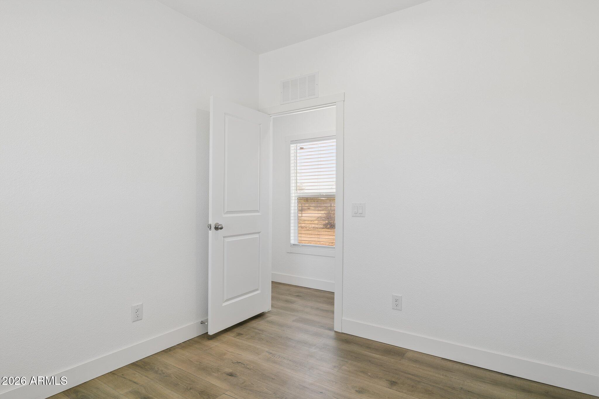 50044 West Century Road Maricopa, AZ 85139 - Photo 25 of 38 a view of an empty room with wooden floor and a window