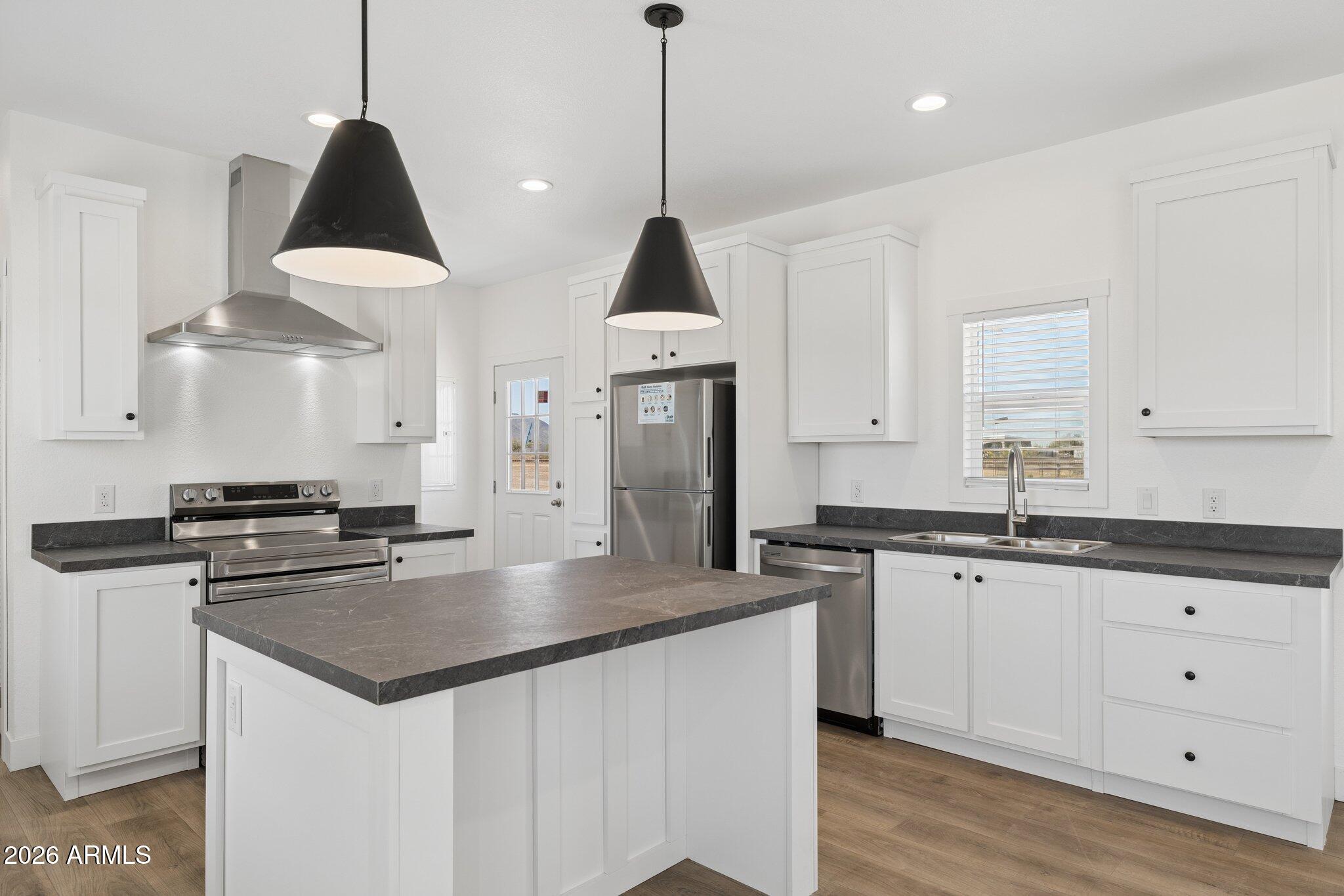 50044 West Century Road Maricopa, AZ 85139 - Photo 3 of 38 a kitchen with stainless steel appliances granite countertop a sink a stove and a wooden floors
