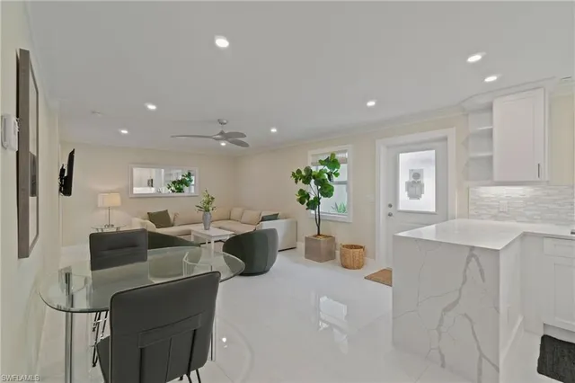 a living room with furniture a potted plant and a kitchen view
