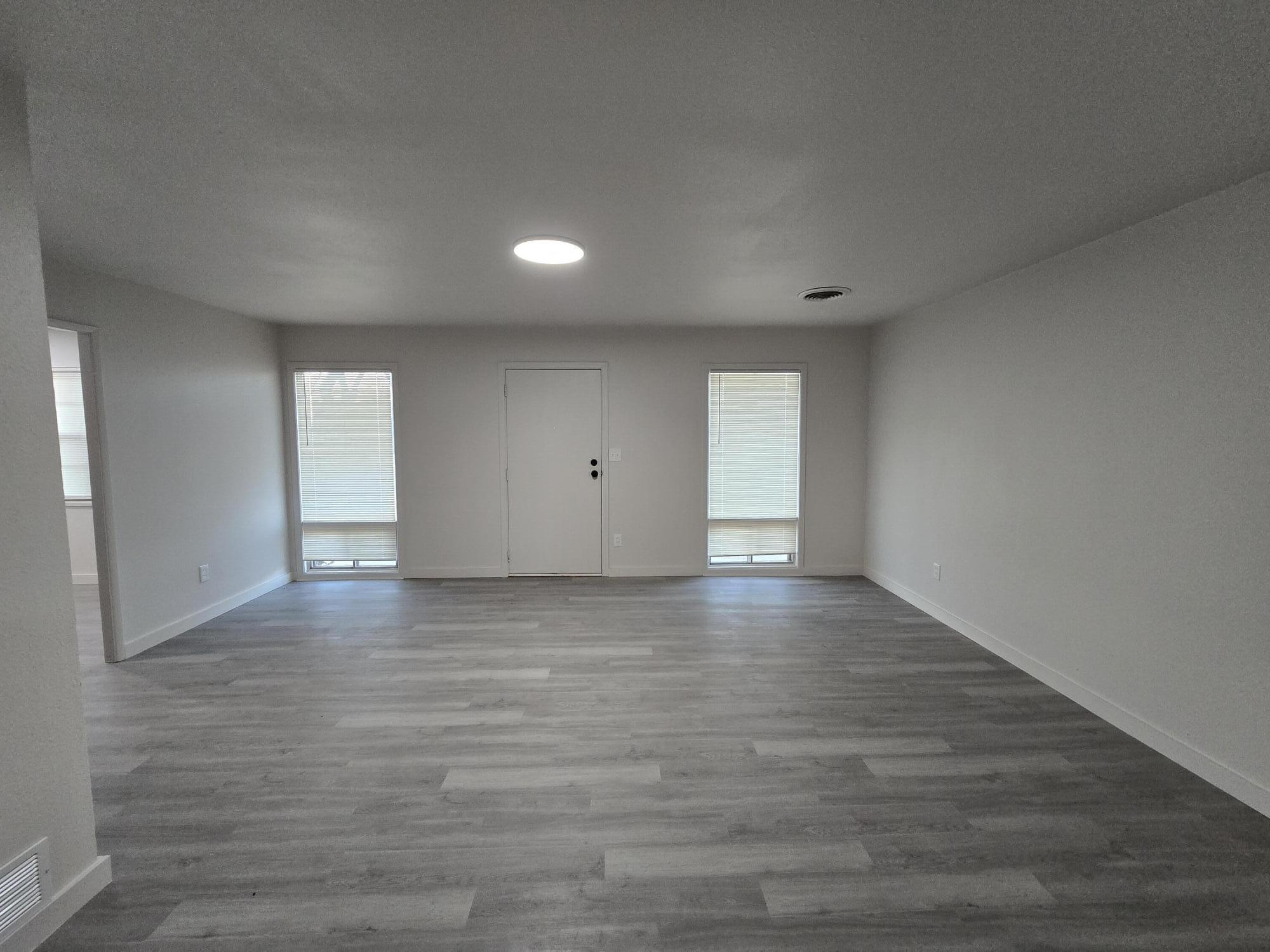205 North 21st Street Lamesa, TX 79331 - Photo 2 of 14 a view of an empty room with window and wooden floor
