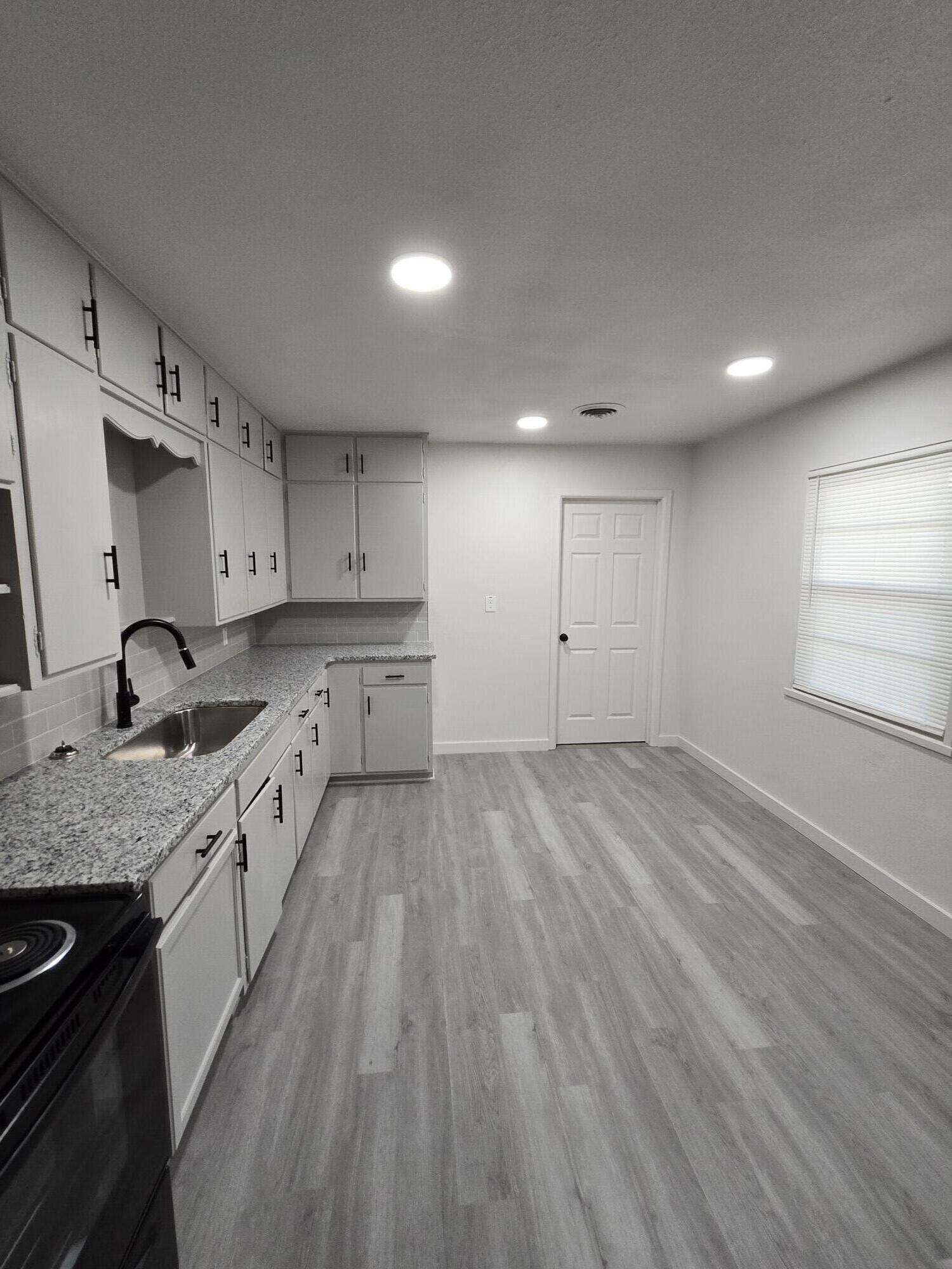 205 North 21st Street Lamesa, TX 79331 - Photo 4 of 14 a large kitchen with stainless steel appliances granite countertop a lot of counter space and wooden floors